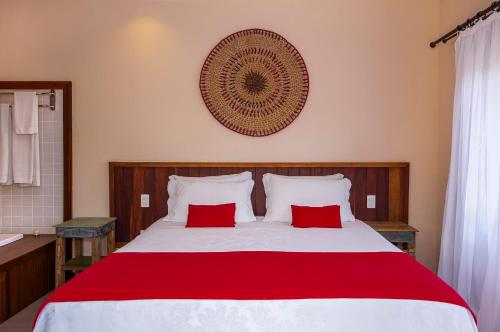 a bedroom with a large bed with two red pillows at Pousada Altamira in Ilhabela