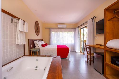 a bathroom with a bed and a tub in a room at Pousada Altamira in Ilhabela