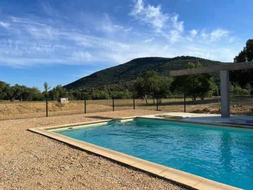 een zwembad in een veld met een berg op de achtergrond bij Mas Grenadine, magnifique villa du Piémont Cévenol in Sauve