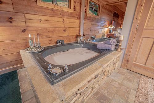 ein Badezimmer mit einer großen Badewanne an einer Holzwand in der Unterkunft Poppy’s Place Cabin in Dandridge