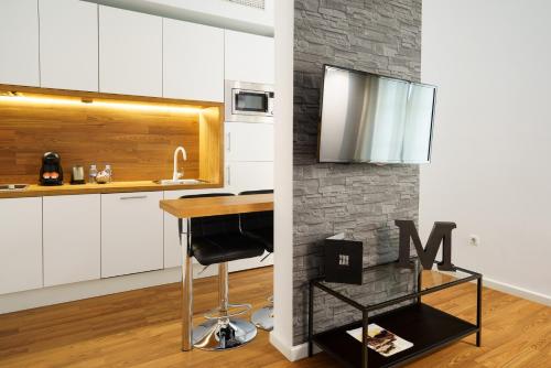 a kitchen with white cabinets and a bar stool at Minimal Rooms by ELE Apartments in Málaga