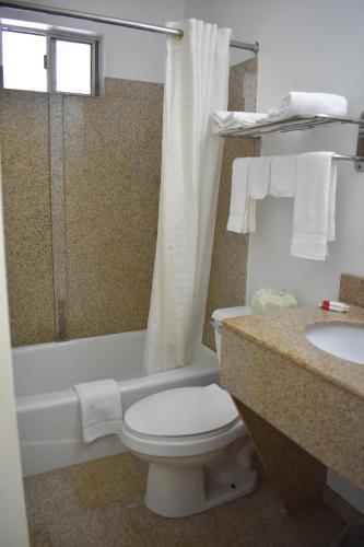 a bathroom with a toilet and a tub and a sink at South Hills Motel in Pittsburgh