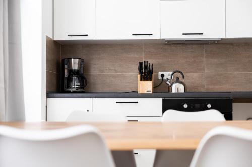 a kitchen with white cabinets and a table and chairs at Apartments am Neuen Theater - Altstadt - Zentral - Küche - Wifi - Powered by Ko-Living in Halle an der Saale