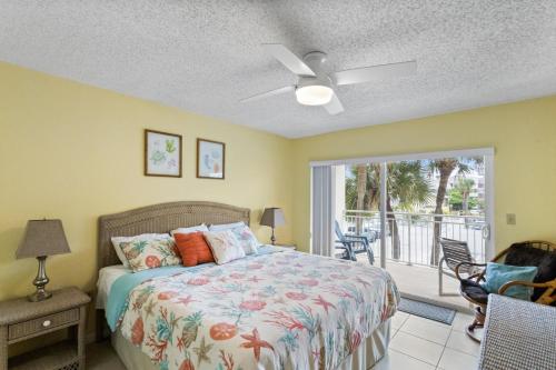um quarto com uma cama e uma porta de vidro deslizante em 106 Madeira Norte Condo em St Pete Beach