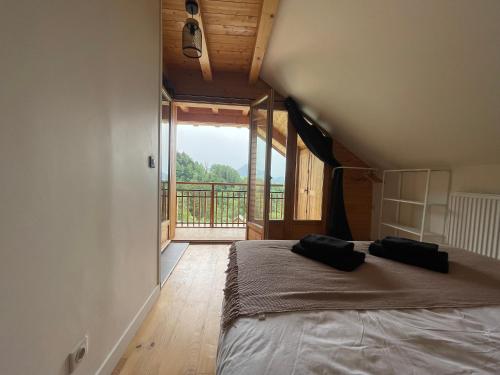 ein Schlafzimmer mit einem großen Bett und einem großen Fenster in der Unterkunft CHALET LA FOUGERE 15 personnes 180m2 bauges Savoie Thoiry in Thoiry