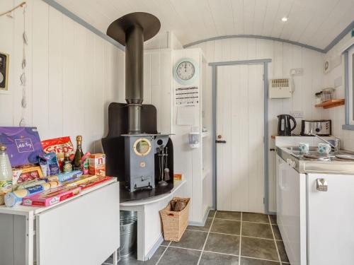 a kitchen with a stove in the corner of a room at The Shepherd's Hut in Aberdyfi