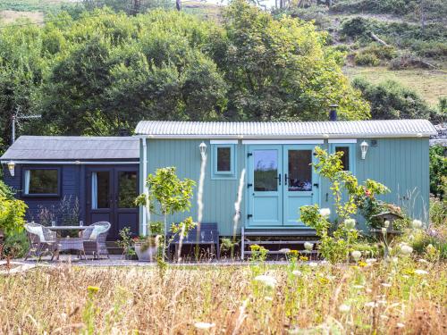 a blue tiny house in the middle of a field at The Shepherd's Hut in Aberdyfi