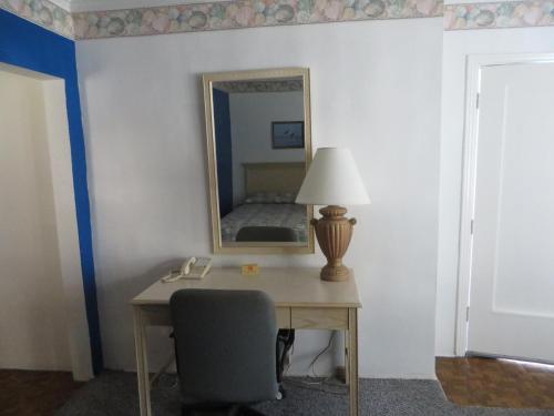 a desk with a lamp and a mirror in a room at Royal Palms Motel in Stuart