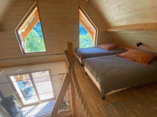twee bedden in een tiny house met ramen bij Chalet l'Empreinte in Saint-Étienne-de-Tinée