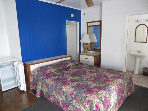 a bedroom with a bed and a blue wall at Royal Palms Motel in Stuart
