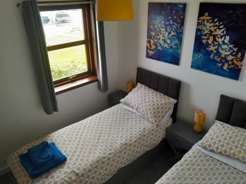 a bedroom with two beds and a window at 2 Harbour Row in Helmsdale