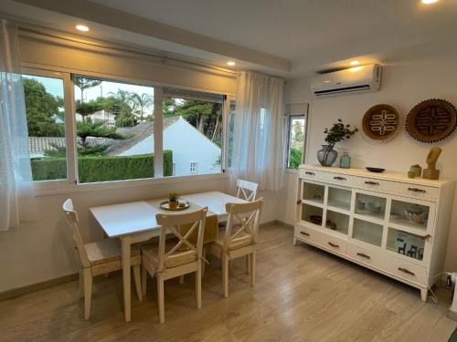 ein Esszimmer mit einem Tisch, Stühlen und einem Fenster in der Unterkunft Casa Violeta - Golf & tenis in Estepona