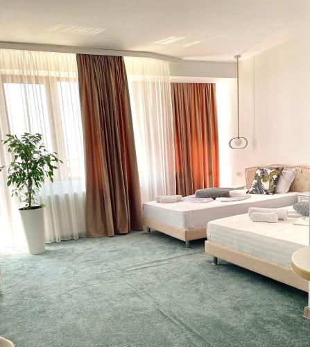 a hotel bedroom with two beds and a potted plant at Caprice Deluxe Accomodation in Drobeta-Turnu Severin