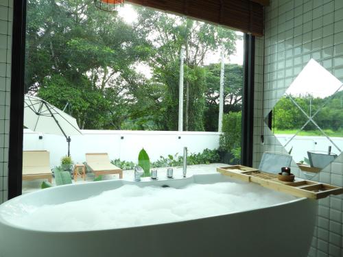 baño con bañera grande y ventana grande en Sleep private khaoyai, en Mu Si