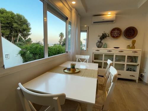 ein Esszimmer mit einem weißen Tisch und einem Fenster in der Unterkunft Casa Violeta - Golf & tenis in Estepona