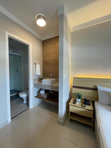 a bathroom with a bed and a sink and a toilet at Flat PRAIA Home Experience Dante Michelini in Vitória