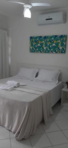 a white bed in a bedroom with a painting on the wall at Casa Moradas de Israel in Porto Seguro