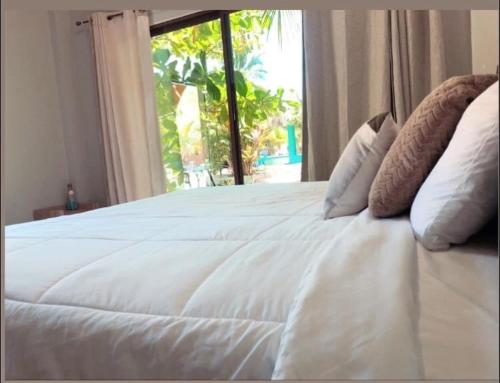 a white bed in a room with a window at Sambo Mambo Beach Hotel in El Cuco