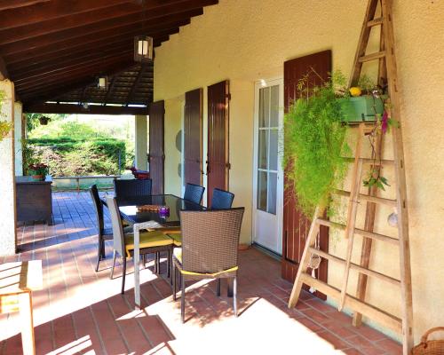 une terrasse avec une table, des chaises et une échelle dans l'établissement Au Coeur Des Arbres, à Fontarèches
