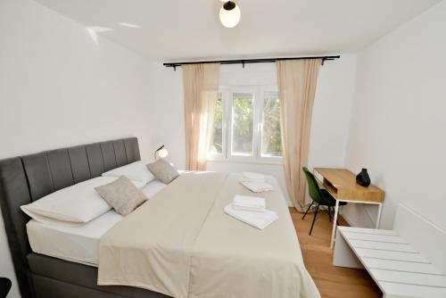 a white bedroom with a large bed and a desk at Apartment Luka in Zadar