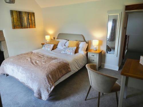 a bedroom with a bed and a desk and a chair at Rose Cottage in Matlock