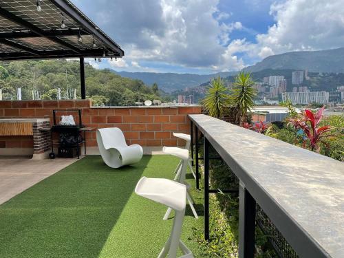 a balcony with two white chairs and grass at Housinn co-living Fatima en Medellín in Medellín