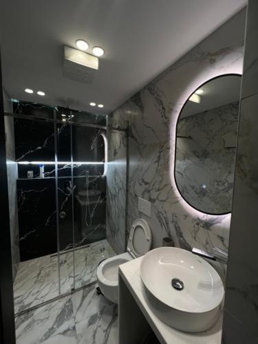 ein Badezimmer mit einem WC, einem Waschbecken und einem Spiegel in der Unterkunft Deluxe apartment bllok in Tirana