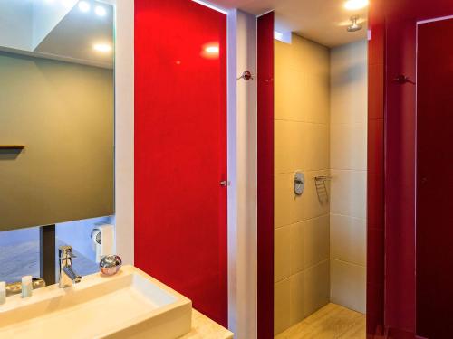 a bathroom with a red shower stall and a sink at Ibis Styles Merida Galerias in Mérida