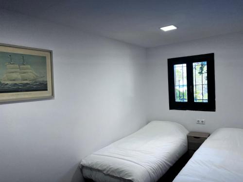 a white room with two beds and a window at La casa Linda con terraza y vistas al mar in Calonge
