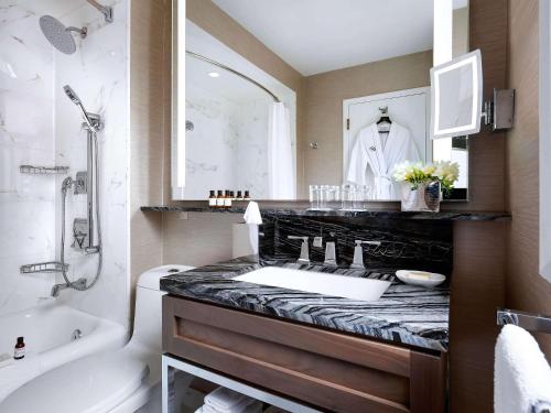 a bathroom with a sink and a toilet and a tub at Fairmont Palliser in Calgary