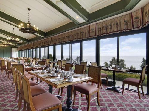 una sala da pranzo con tavoli, sedie e finestre di Fairmont Le Manoir Richelieu a La Malbaie