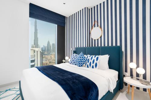 - une chambre avec un lit bleu et blanc et une fenêtre dans l'établissement Ultimate Stay / 4 Beds / Burj Khalifa View / Ultra Modern / Business Bay, à Dubaï