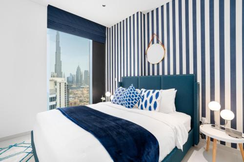 a bedroom with a blue and white bed and a window at Ultimate Stay / 4 Beds / Burj Khalifa View / Ultra Modern / Business Bay in Dubai