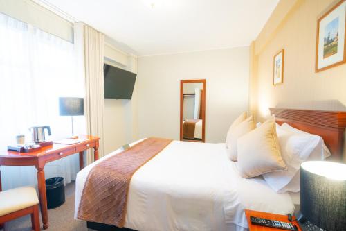 a hotel room with a bed and a desk and a window at El Tumi Hotel in Huaraz