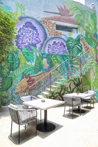 two tables and two chairs in front of a mural at Agata Hotel Boutique & Spa in Mexico City