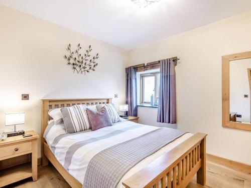 1 dormitorio con 1 cama grande y espejo en The Granary, en Llanfair Caereinion