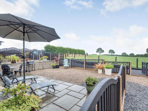 a patio with two benches and an umbrella at The Granary in Llanfair Caereinion