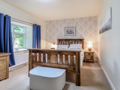 a bedroom with a wooden bed and blue curtains at Cobbler's Cottage in Pickering
