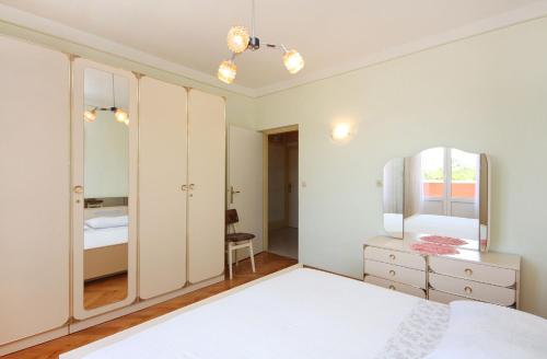 a bedroom with a white bed and a mirror at Apartment Kampor 4972b in Kampor