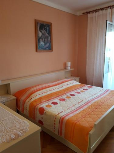a bedroom with a bed with an orange blanket at Apartments with parking space Kampor, Rab - 4972 in Kampor