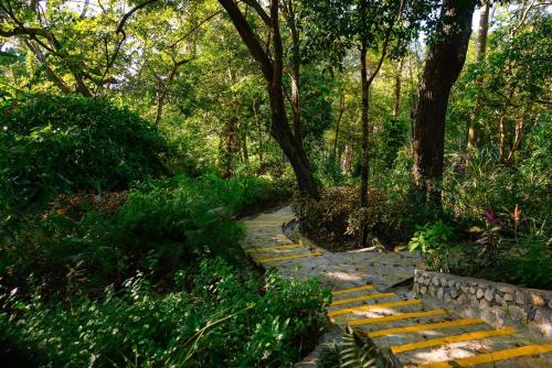 a stone path in a park with trees and bushes at Hacienda La Huerta Puerto Plata, 1 BDR in San Felipe de Puerto Plata