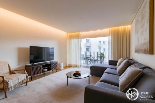 a living room with a couch and a tv at Home Azores - Coliseu Residences in Ponta Delgada