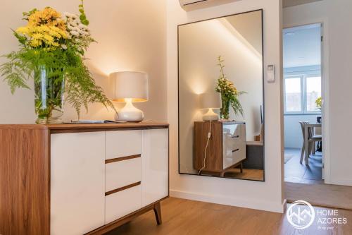 una habitación con espejo y un tocador con flores. en Home Azores - Coliseu Residences en Ponta Delgada