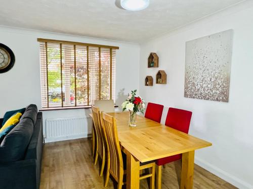 a dining room with a wooden table and red chairs at Beautiful 3 bedroom house with garden + Parking in Oxford