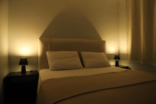 a bed with two white pillows and two lamps at Edícula Próxima a Praias! in São Luís