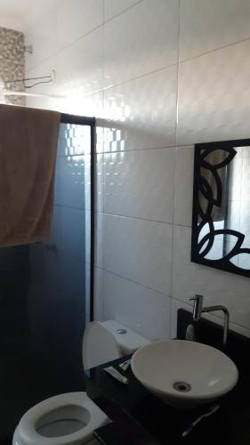 y baño con aseo blanco y lavamanos. en Casa condominio Rancho de Jacone en Maricá