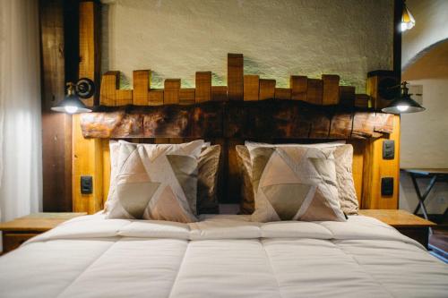 a bedroom with a large white bed with two pillows at Chalés Requinte da Mantiqueira in Monte Verde