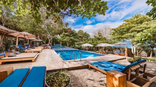 een zwembad met ligstoelen en parasols bij Blue Apple Beach in Tierra Bomba