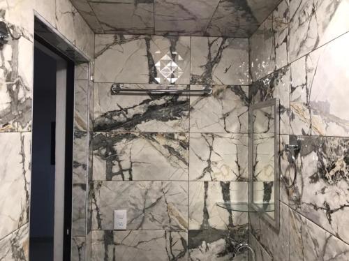 a bathroom with a marble wall with a shower at HOTEL NUEVA LUNA in Zacatlán