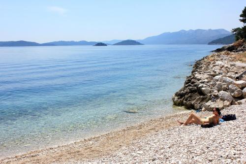 a woman sitting on a beach near the water at Apartments with parking space Savar, Dugi otok - 8127 in Savar
